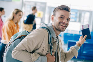 Junger Reisender am Flughafen mit Boarding-Pass in der Hand
